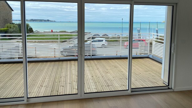 Ein Balkon mit Meerblick, ein Parkplatz und ein Gebäude im Hintergrund.