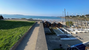 Blick auf die Küste mit einem gepflasterten Weg, Strand und einer Reihe von Booten.