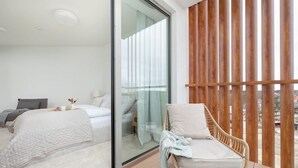 A bedroom with a bed, a chair, and a sliding glass door leading to a balcony.