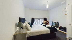 Ein modernes Hotelzimmer mit Bett, Nachttisch, Lampe und einem Vorhangfenster.