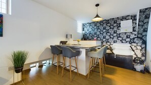 Eine moderne Küche mit Barbereich, Holzboden und floralem, schwarzem Wandpapier.