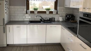 Una cocina moderna con armarios blancos, un lavamanos de acero inoxidable y un horno empotrado.