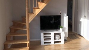 Una escalera conduce a una plataforma donde hay un televisor de pantalla plana sobre un mueble blanco.