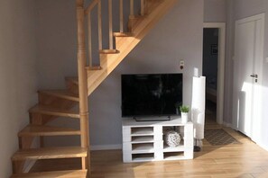 A staircase leading to a landing with a flat-screen TV on a white entertainment unit.