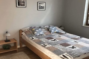 A bedroom with a bed, pillows, a bedside table, and a lamp. - Holiday home with a large garden and playground (Debina)