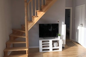 A staircase leading to a landing with a flat-screen TV on a white entertainment unit. - Holiday home with a large garden and playground (Debina)