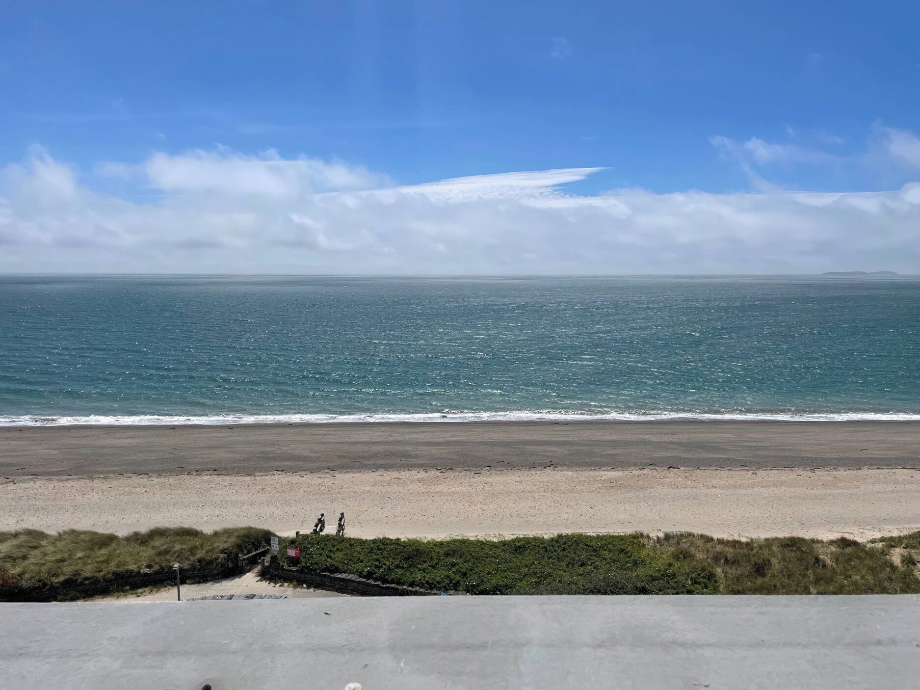 A beach with a clear view of the ocean and a distant island.