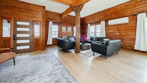 Ein geräumiges Wohnzimmer mit Holzwänden und hoher Decke, ausgestattet mit zwei Sofas, einem Couchtisch und einem Teppich.