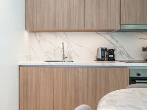 Eine moderne Küche mit Holzausstattung, einer Marmor-Spritzschutzwand und einer Kaffeemaschine auf der Arbeitsfläche.