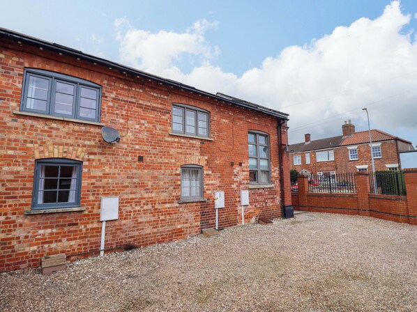 A red brick building with multiple windows and a gravel driveway.