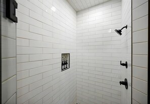 Un bagno con pareti piastrellate in bianco e una doccia.
