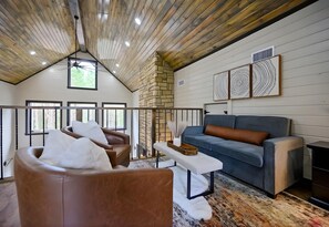 A spacious living room with a stone fireplace, a blue sofa, and a brown leather chair. - Hot Tub | Fire Pit | Foosball | Arcade Machine (Broken Bow)