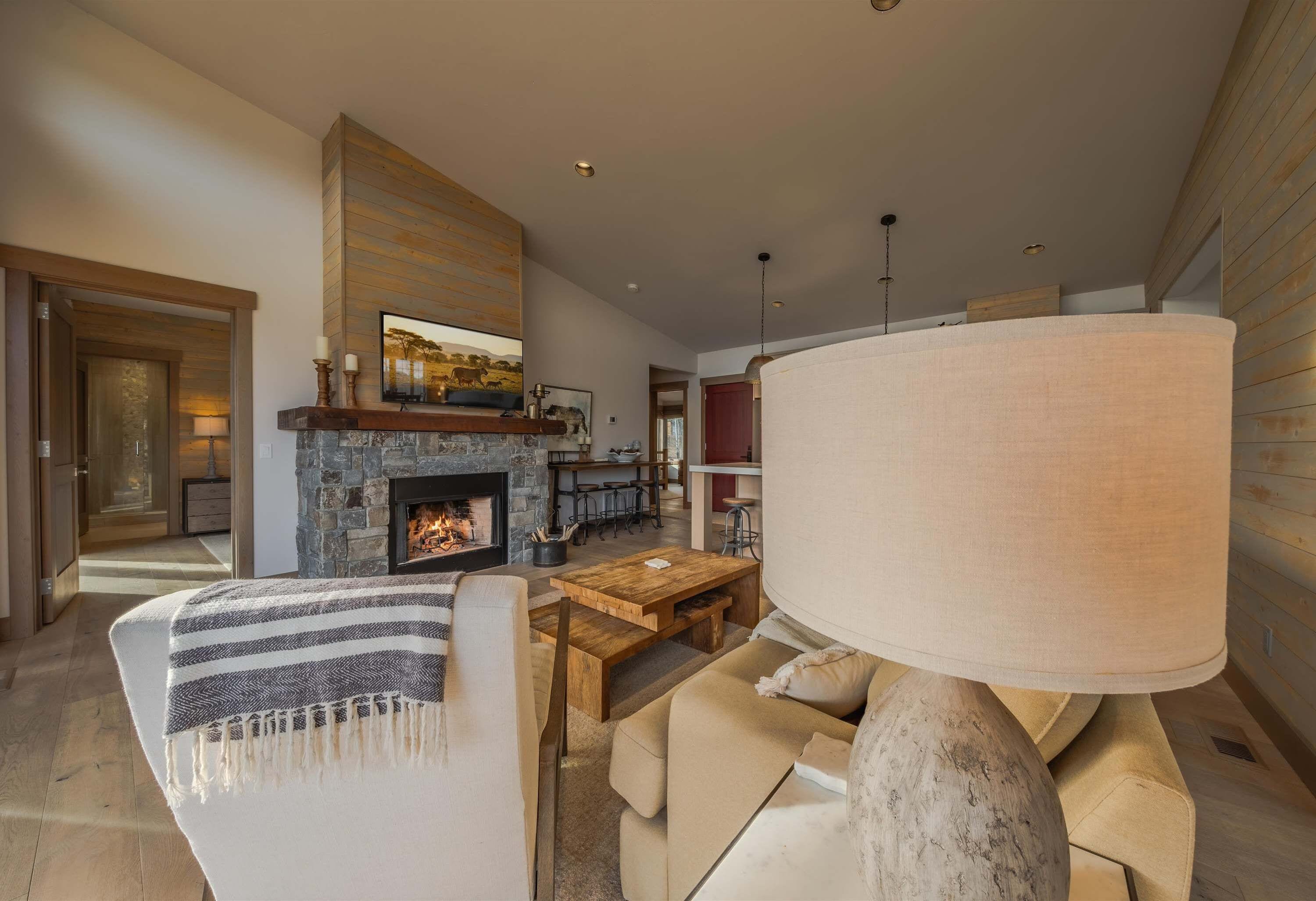Un salon moderne avec une cheminée, un canapé, une table basse et une lampe.