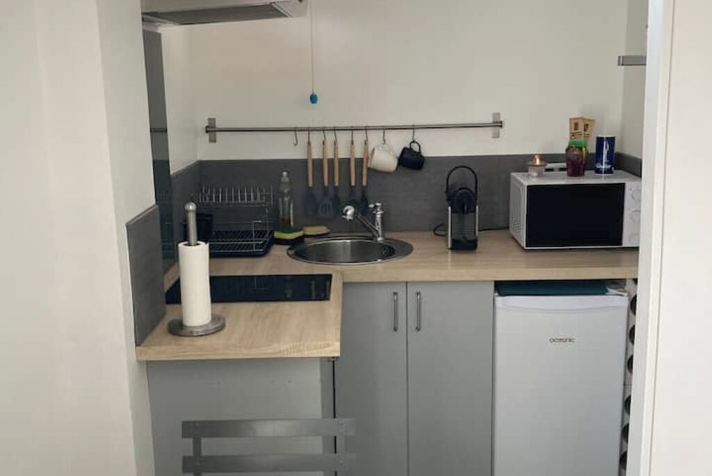 A compact kitchen with a sink, microwave, and a small refrigerator.