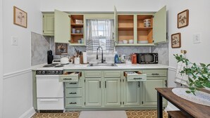 A compact kitchen with green cabinets, a white stove, and a microwave. - 1br apt - heart of Uptown Maumee w/ Fiber WiFi. #3 (Maumee)