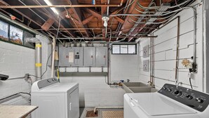 A laundry room with a washing machine, dryer, and utility room with electrical panels and pipes. - 1br apt - heart of Uptown Maumee w/ Fiber WiFi. #3 (Maumee)