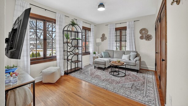 A living room with a sofa, a coffee table, a TV, and a window with curtains. - 1br apt - heart of Uptown Maumee w/ Fiber WiFi. #3 (Maumee)