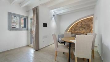 A dining area with a round table, chairs, and a stone wall.