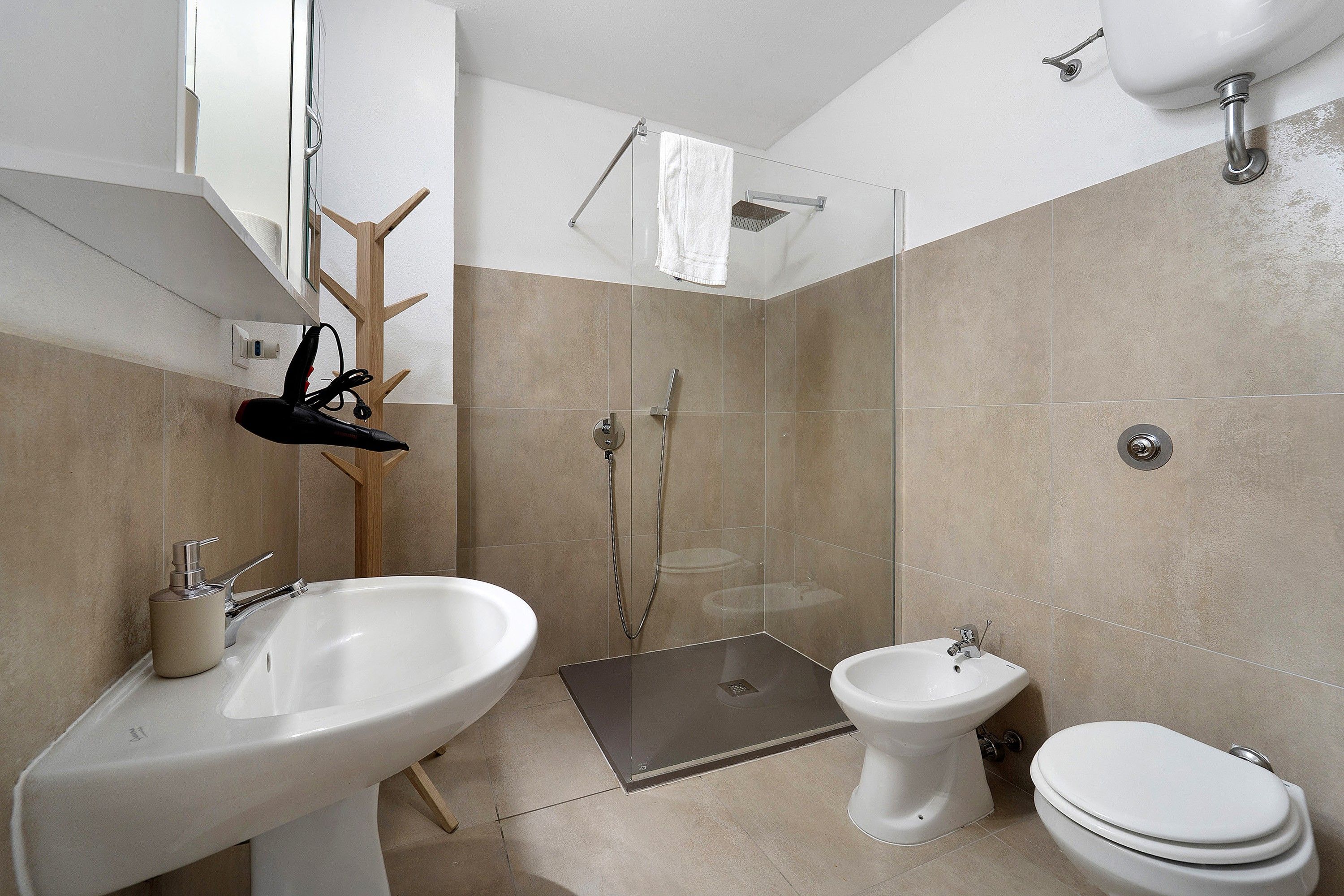 A modern bathroom with a large sink, a bidet, a toilet, and a glass-enclosed shower area.
