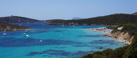 Un paisaje costero con aguas azules cristalinas, barcos y una zona de playa.