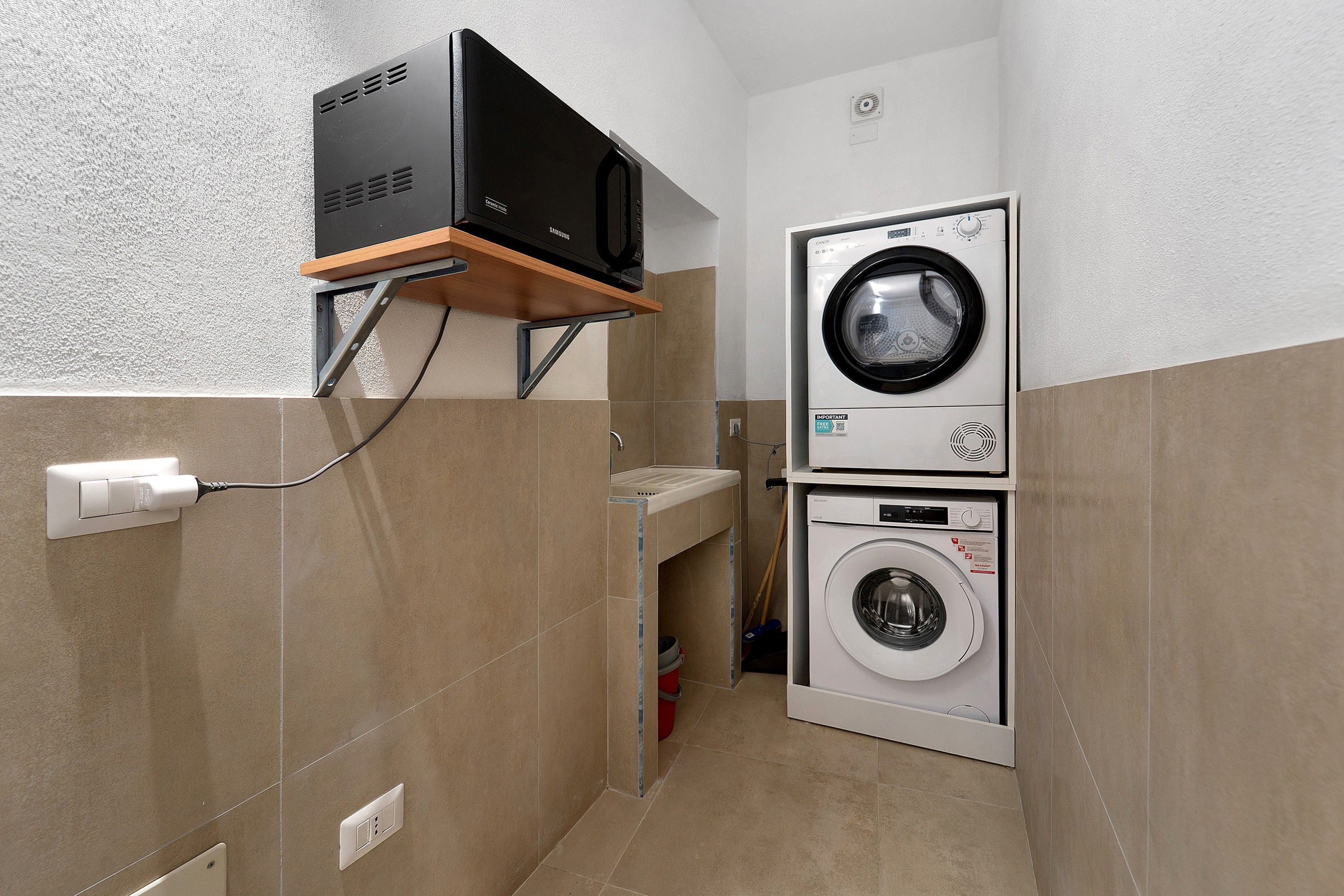 Une petite buanderie comprenant un micro-ondes posé sur une étagère, un lave-linge et un sèche-linge.