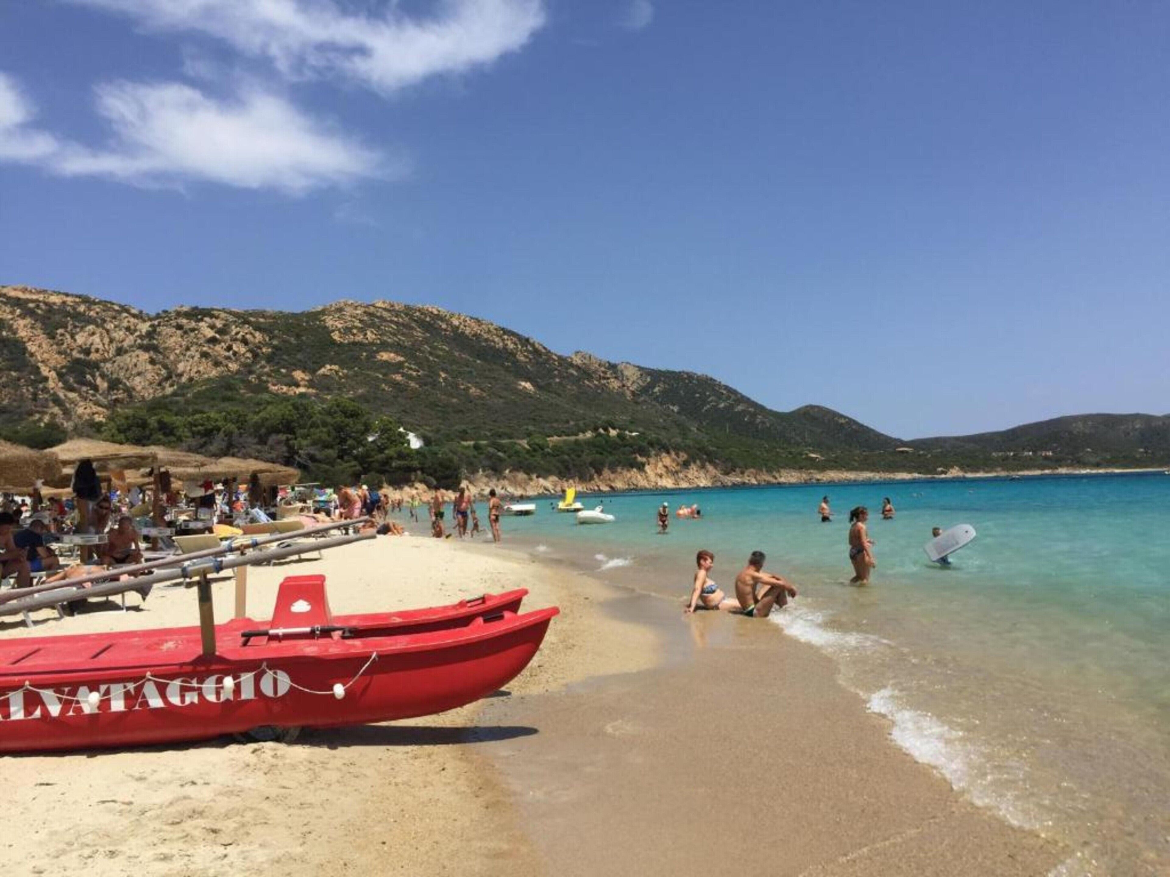 A beach with a red boat labeled 'LIVATAGGIO' and people in the water.