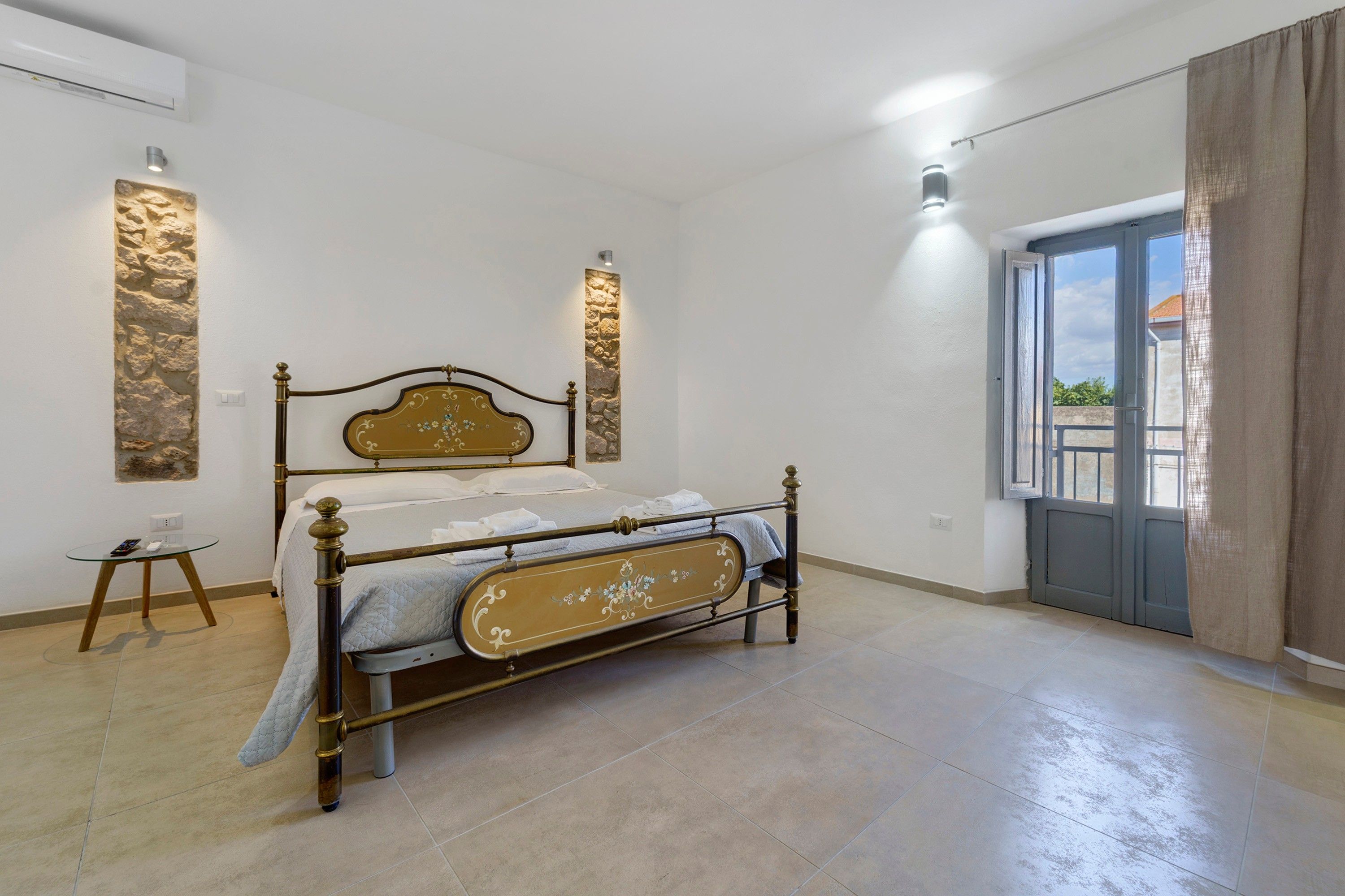 Une chambre à coucher avec un lit, une petite table et une porte donnant sur un balcon.