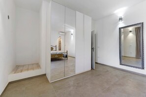 A room with a bed, a wardrobe, a mirror, and a tiled floor. - Via Roma 50 - Apartment 10 (Nuraxi Figus)