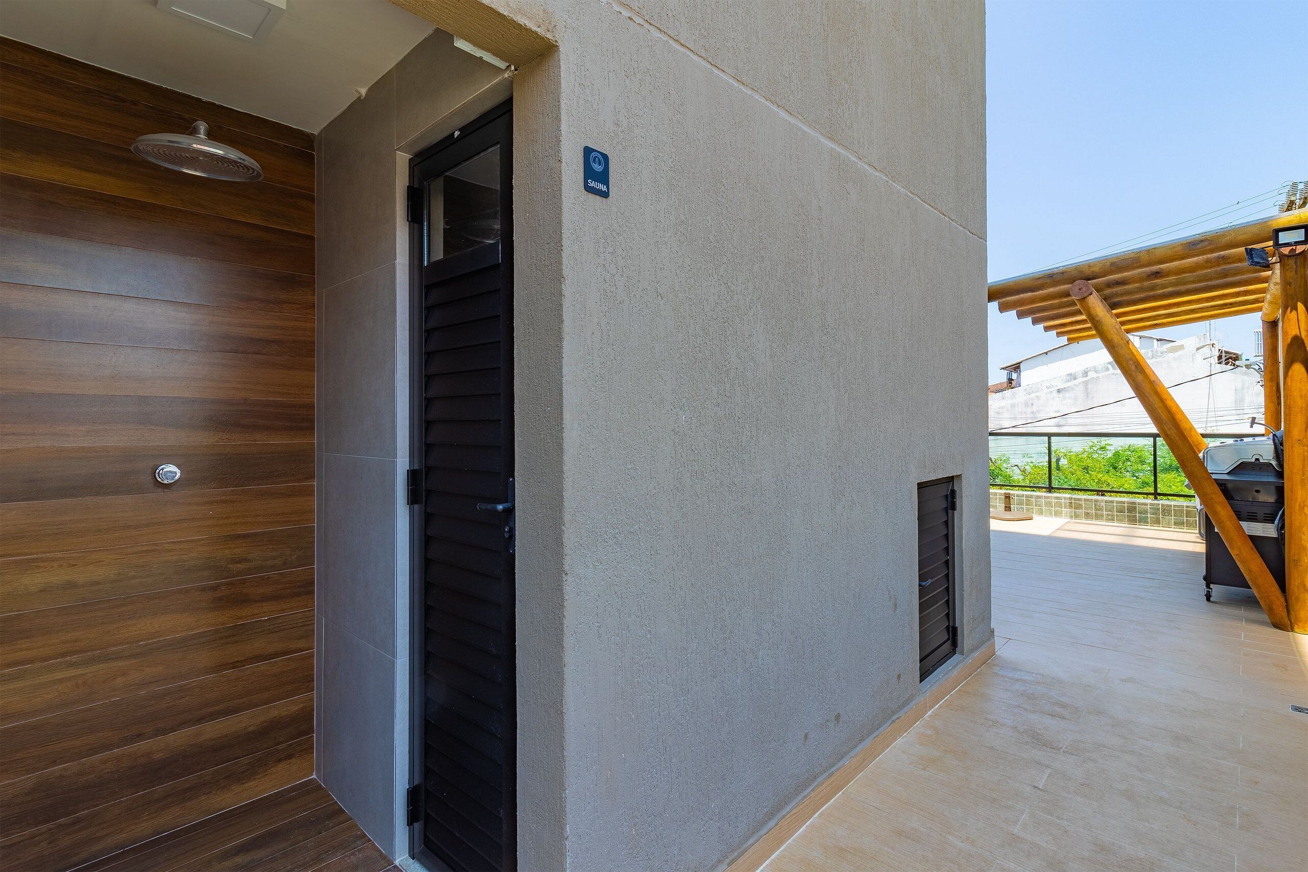 A modern building with a wooden door, a metal vent, and a sign indicating a sauna.