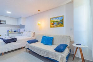 A modern hotel room with two beds, a small kitchenette, a dining table, and a painting on the wall. - Villa Del Mar #206 - Quadruple by Carpediem (Ipojuca)