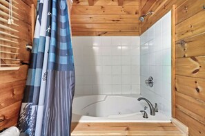A wooden cabin bathroom with a bathtub, a shower, and a window with blinds. - 🦌 The Mellow Moose | Hot Tub, Mountain Views & Game Loft, Near Dollywood (Pigeon Forge)