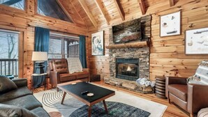 A cozy cabin interior with a stone fireplace, wooden walls, and a comfortable seating area. - *Relaxing  2BD Cabin Near TOWN | Hot Tub + VIEWS* (Pigeon Forge)