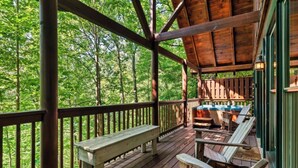 A wooden deck with a bench and chairs, overlooking a forested area. - *Relaxing  2BD Cabin Near TOWN | Hot Tub + VIEWS* (Pigeon Forge)
