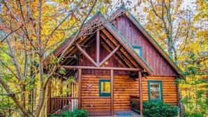 A rustic log cabin with a steeply pitched roof, a porch, and a star decoration on the wall. - *Relaxing  2BD Cabin Near TOWN | Hot Tub + VIEWS* (Pigeon Forge)