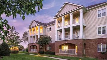 A multi-story residential building with a brick facade, multiple balconies, and a well-maintained lawn.