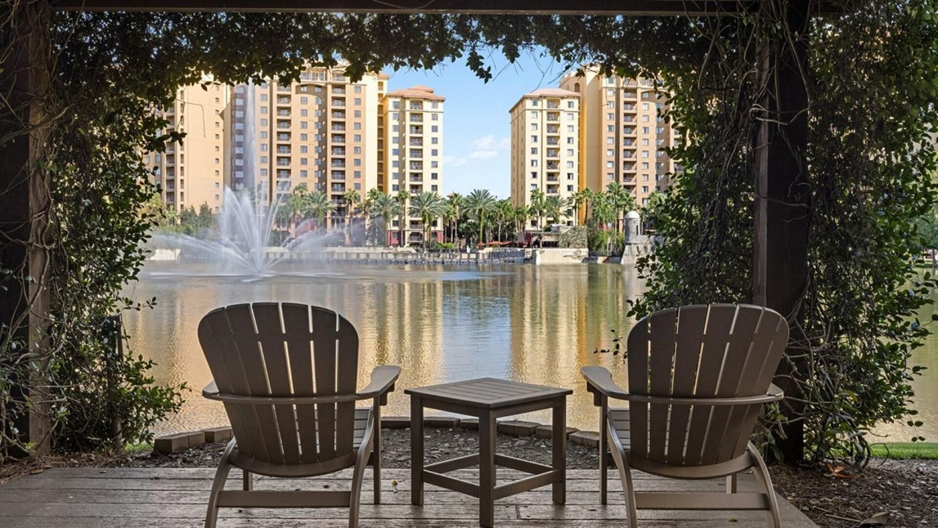 Un belvédère abritant deux fauteuils Adirondack et une petite table, d’où l’on peut admirer une fontaine et un plan d’eau, avec des immeubles de grande hauteur en arrière-plan.