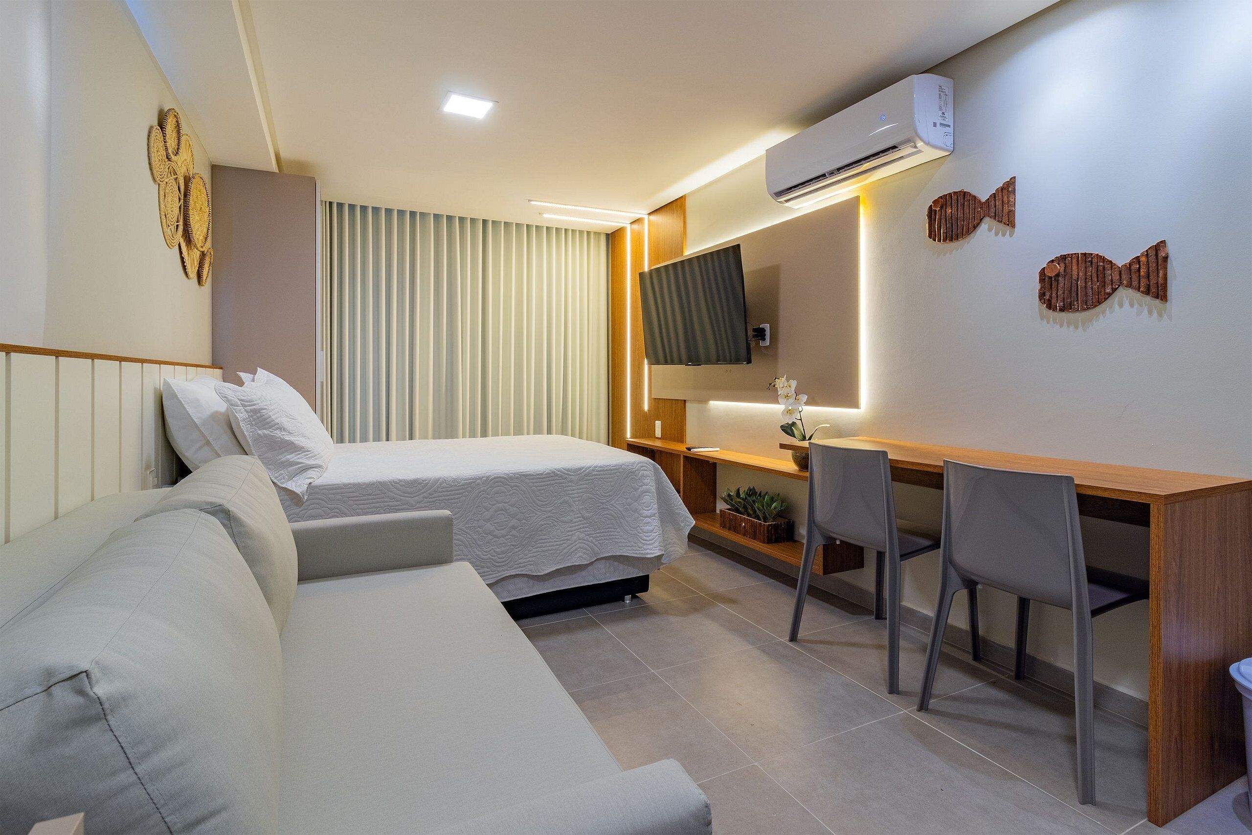 A hotel room with two beds, a desk, a chair, and a TV.