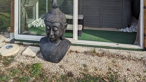 Un edificio moderno con puerta de vidrio, un jacuzzi y una estatua de Buda en el exterior.