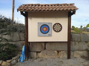 A dartboard and a target board mounted on a wall with a tiled roof. - Bastide Saint-Germain (Saint-Ambroix)