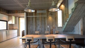 A modern kitchen with a large island, wooden accents, and pendant lighting. - Architect-designed 4-bedroom villa with pool in palombaggia with sea view (Porto-Vecchio)