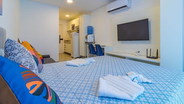 Una habitación de hotel con cama, escritorio, silla, televisor y aire acondicionado.