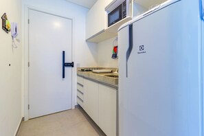 Eine kleine Küche mit weißen Schränken, einer Mikrowelle und einem Kühlschrank.