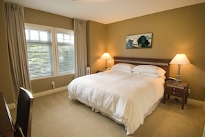 Quarto com uma cama grande, duas mesas de cabeceira com luminárias, um quadro na parede e uma janela com cortinas.