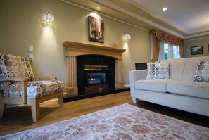 A living room with a fireplace, a sofa, two patterned chairs, and a rug.