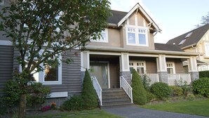 A two-story house with a front porch, a driveway, and a well-maintained lawn. - King bed, ensuite bathroom with shower (Vancouver)