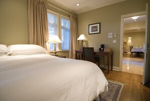 A hotel room with a large bed, two bedside lamps, a desk with a chair, and a framed picture on the wall.