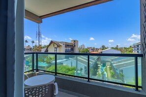 Ein Balkon mit Glasgeländer, einem Tisch und einem Stuhl.