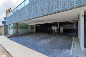 A modern building with a tiled facade, a gated entrance, and a paved parking area. - Villa Del Mar #203- Flat With Balcony by Carpediem (Ipojuca)