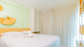 A hotel room with a bed, a wall-mounted fan, and a window with curtains. - Porto Prime #308 - Studio Confort by Carpediem (Ipojuca)