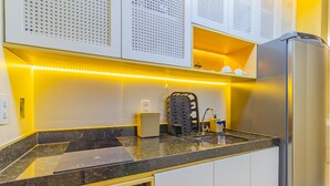A modern kitchen with a built-in stove, a refrigerator, and a coffee machine. - Porto Prime #308 - Studio Confort by Carpediem (Ipojuca)